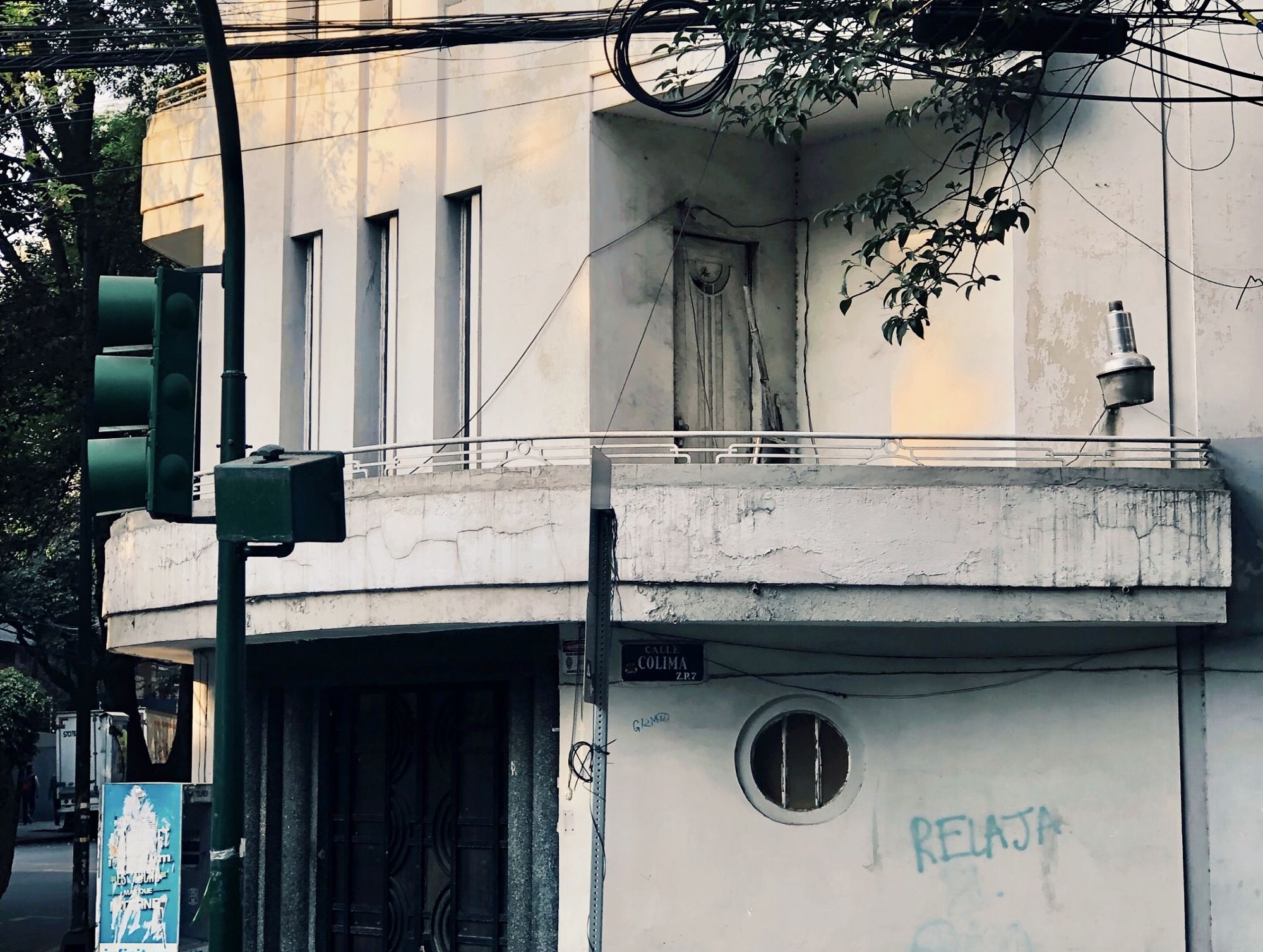 Sunlit corner of an art deco building on Calle Colima, with a curved balcony and a round porthole window